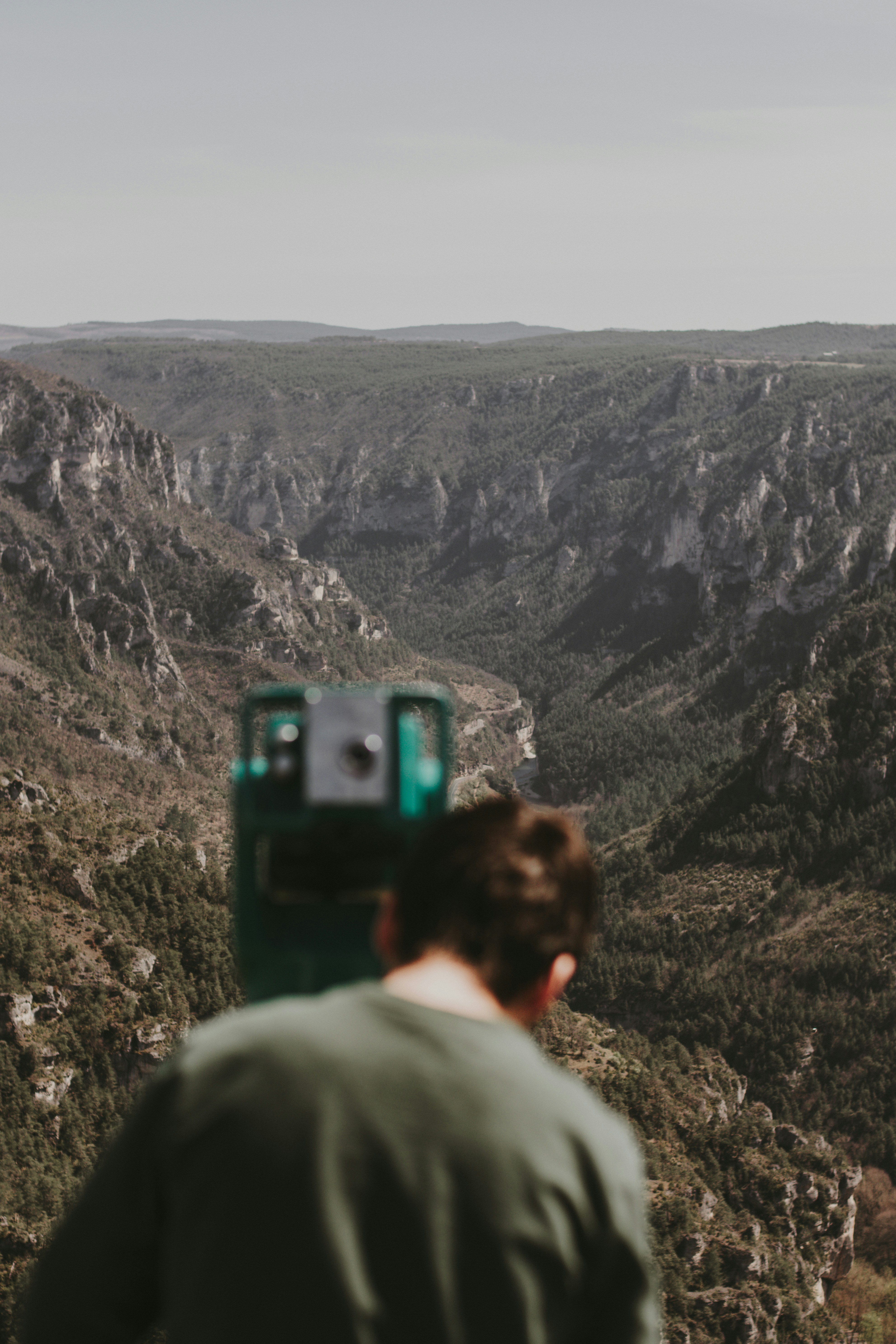 man in gray hoodie standing on rocky mountain during daytime